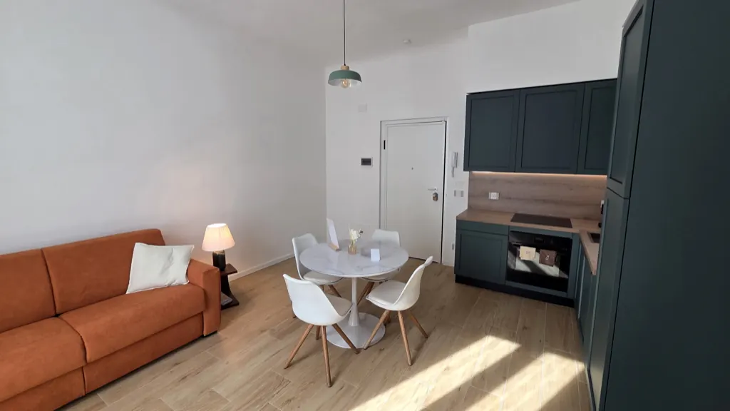 Cucina attrezzata dell'appartamento ai Navigli, con ante verdi, piano cottura, forno e lavastoviglie