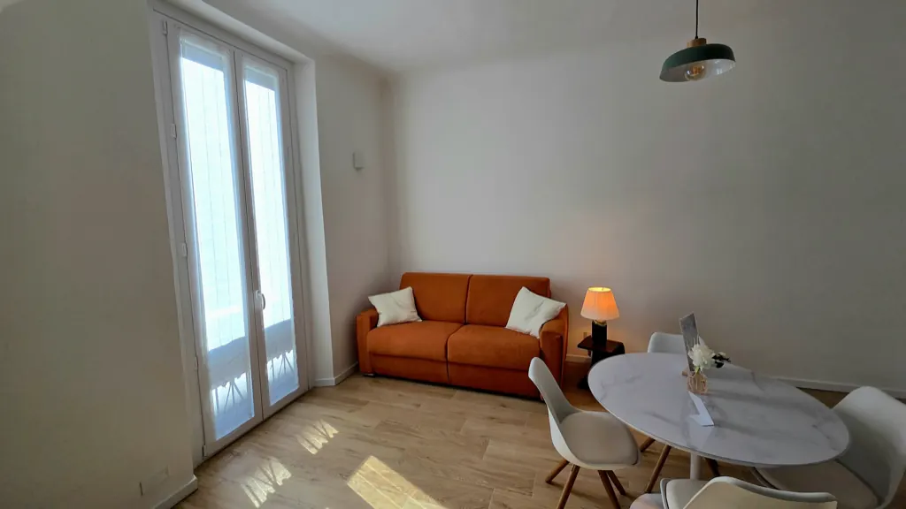 Soggiorno dell'appartamento Stay Navigli a Milano, con divano letto arancione, tavolo rotondo e portafinestra